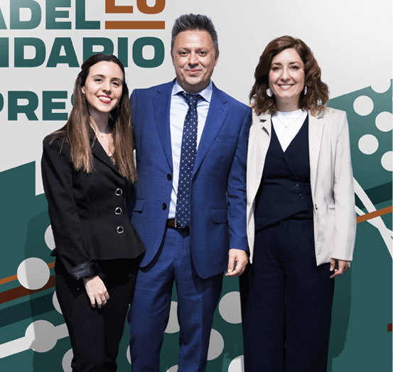 Tres personas adultas vestidas formalmente posan sonrientes frente a un cartel que anuncia un torneo solidario de p del para empresas. Descripci n generada con IA