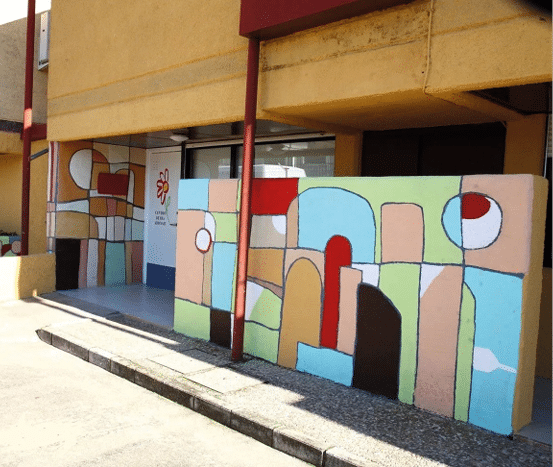 Fachada de edificio con murales coloridos de formas geom tricas y l neas negras que crean un dise o abstracto. Descripci n generada con IA